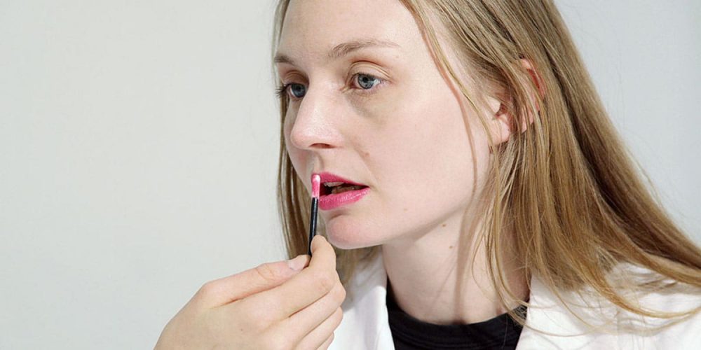 closeup of a fair-skinned blonde woman applying lipstick