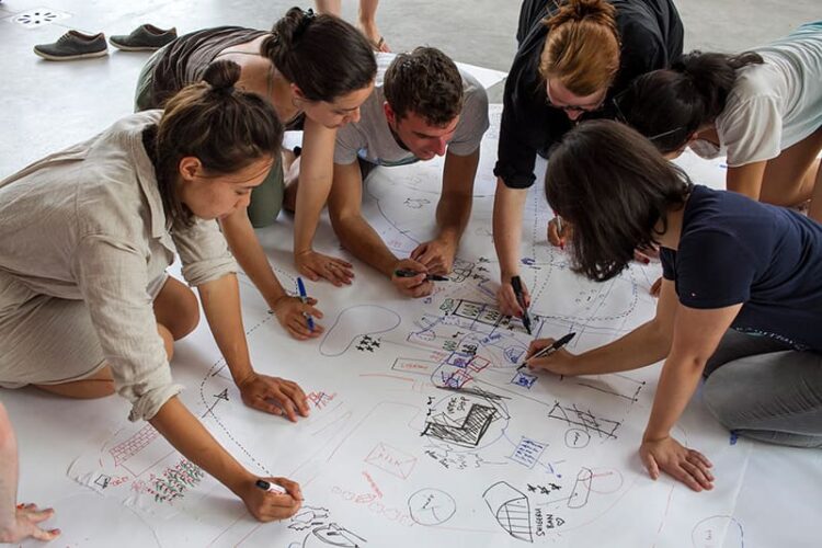 Group of people collaborating on a drawing on the floor