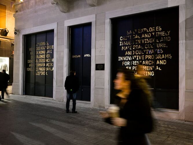 People walking past a display of illuminated text